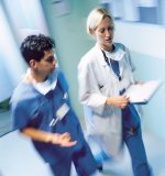 Picture of a male Nurse an a female Physician walking down a hospital hallway talking
