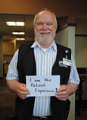 Picture of a male patient holding a sign that says:
I am the Patient Experience!
