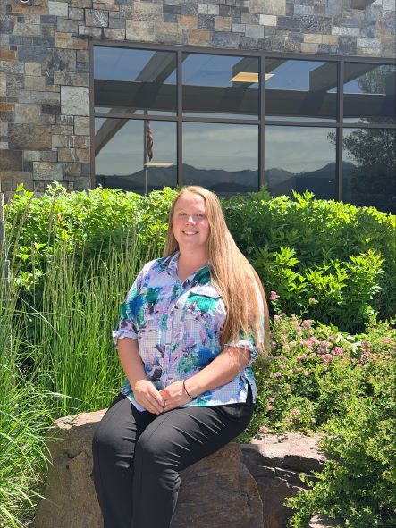 Brooke Bolin, new Foundation Director, sitting outside of the hospital o a rock